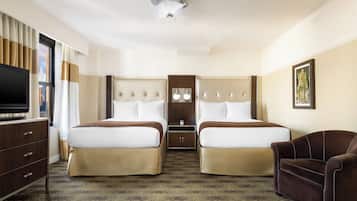 A hotel room with two beds, a TV, a desk, and a chair.