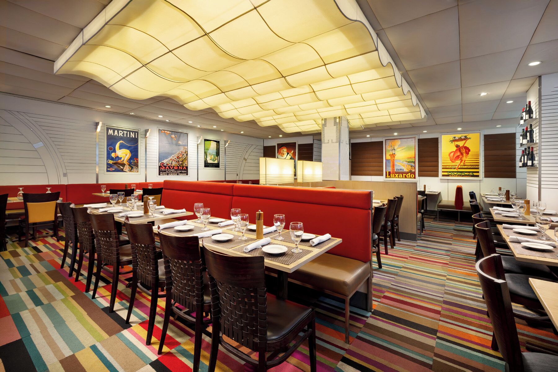 Een restaurant met zitplaatsen, tafels en een kleurrijk gestreept tapijt.