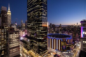 A cityscape with high-rise buildings, including a prominent skyscraper with illuminated windows and a circular building with a central atrium.