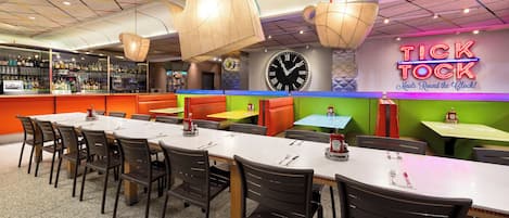 Um restaurante com várias áreas de estar, incluindo cabines e mesas, e um bar com uma variedade de garrafas.