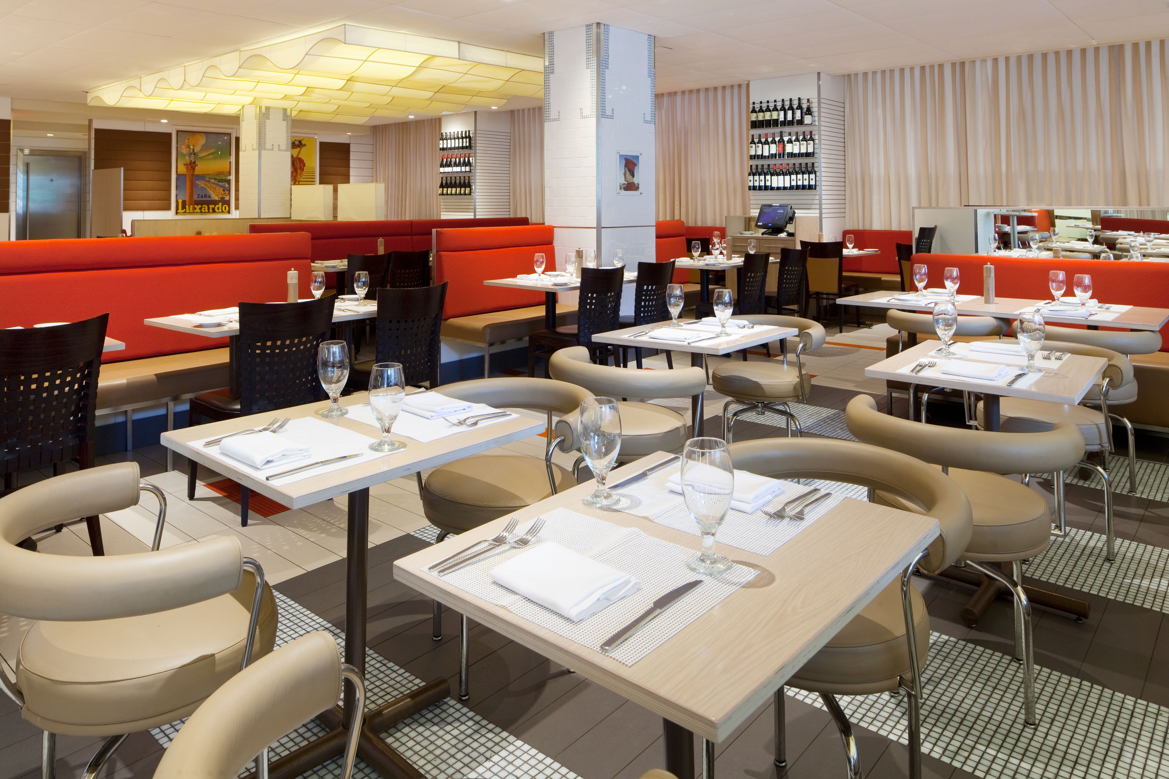 Un restaurante con cabinas y mesas, cada una dispuesta con cubiertos y vasos.