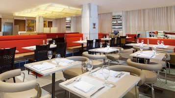 Un restaurante con cabinas y mesas, cada una dispuesta con cubiertos y vasos.