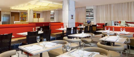 Un restaurante con cabinas y mesas, cada una dispuesta con cubiertos y vasos.