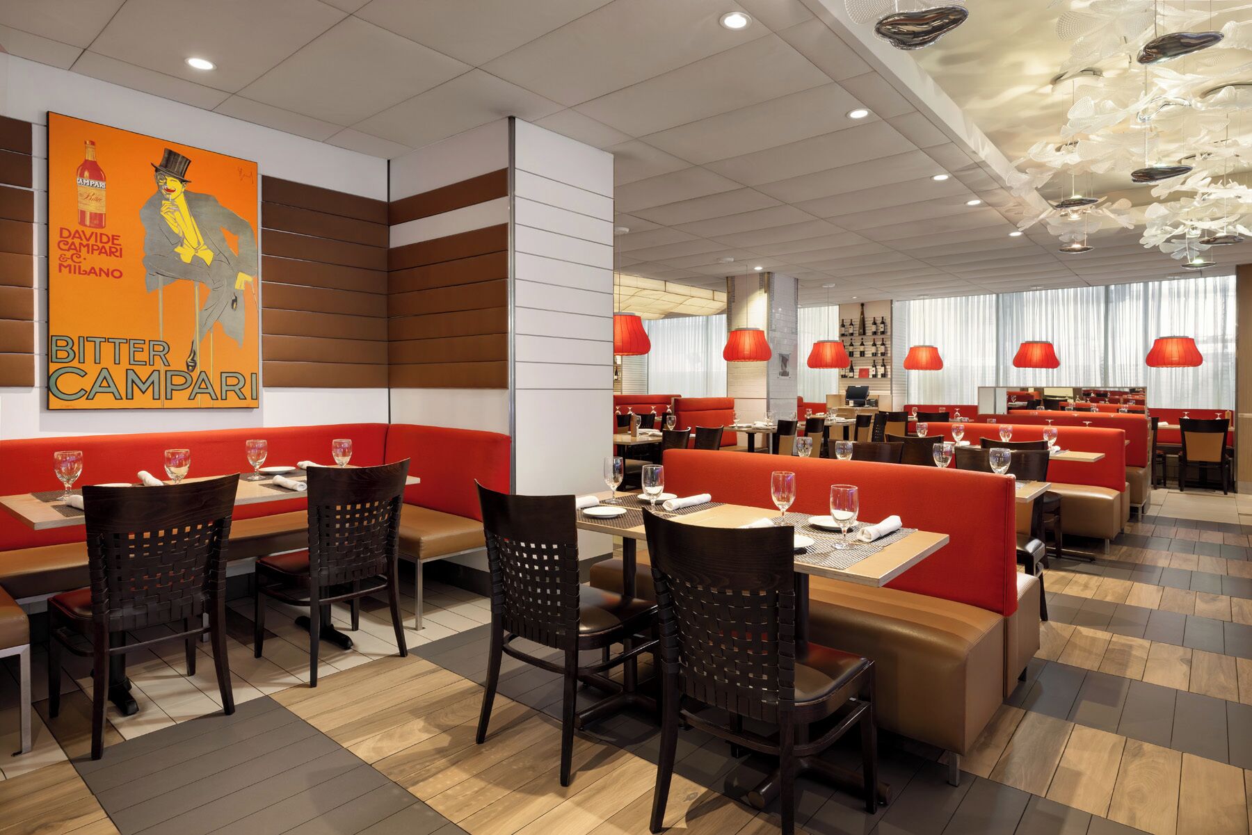 A restaurant interior with booths and tables, red upholstered seating, and a prominent poster on the wall.