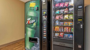 Two vending machines, one with a 7UP logo and the other with a variety of snacks. - Studio 6 Corporate Extended Stay Indianapolis, IN - North Carmel (Carmel)
