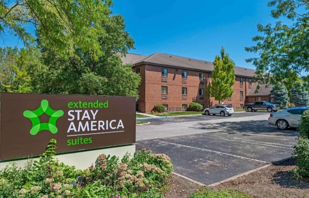 Segnaletica per Extended Stay America Suites, con un parcheggio e un edificio in mattoni sullo sfondo.