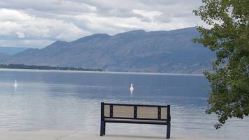 A bench by a calm lake with mountains in the background.
