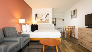 Een hotelkamer met een bed, een bank, een kleine tafel, een televisie en een bureau met stoelen.