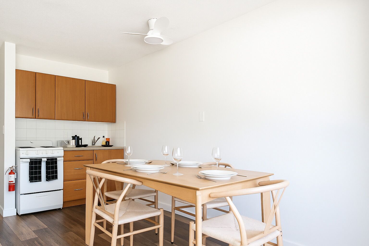 A kitchen with wooden cabinets, a white stove, and a dining table set with plates and glasses.