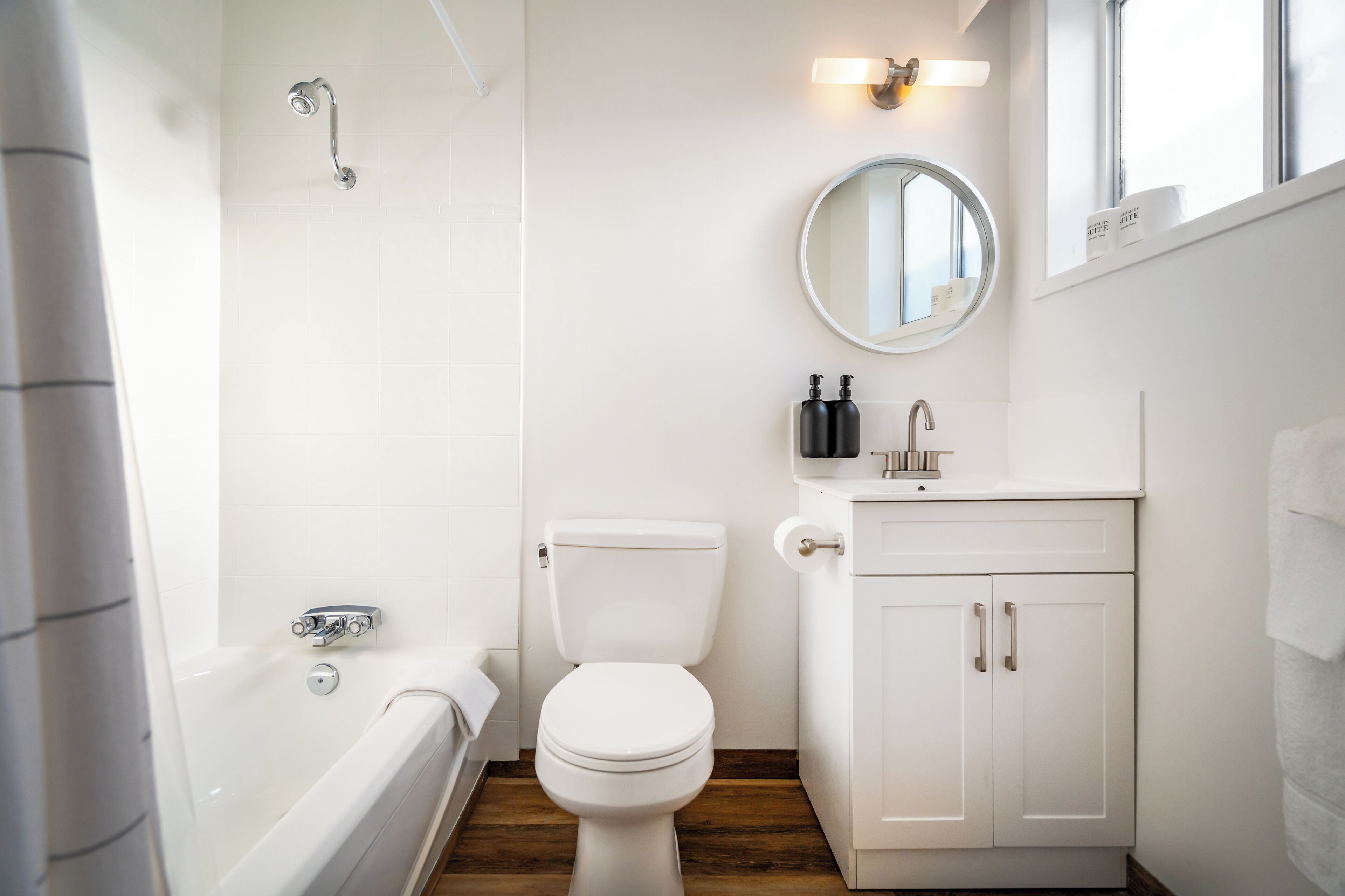 A bathroom with a white toilet, a bathtub, and a sink with a mirror above it.