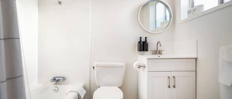 A bathroom with a white toilet, a bathtub, and a sink with a mirror above it.