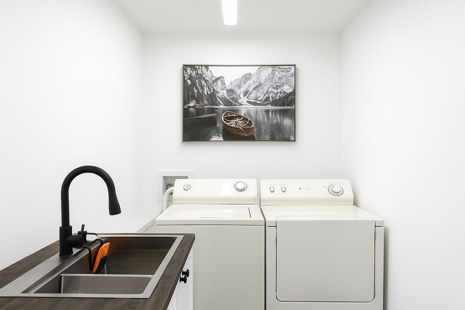 Un área de lavandería con lavadora, secadora y lavabo.