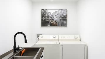 Un área de lavandería con lavadora, secadora y lavabo.