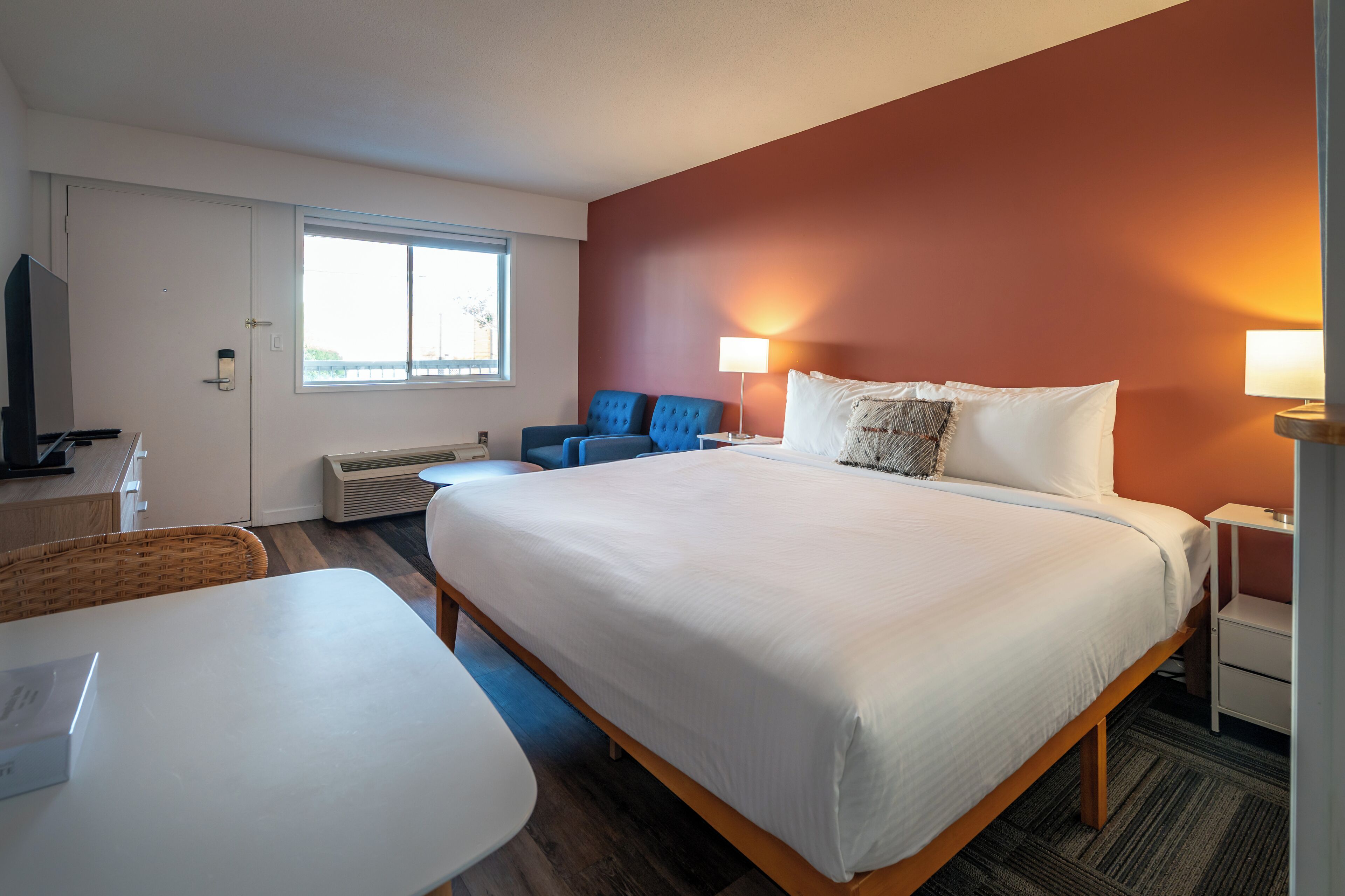 A hotel room with a large bed, a desk, a chair, and a TV.