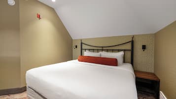 A hotel room with a single bed, a nightstand, a wall-mounted lamp, and a ceiling light.
