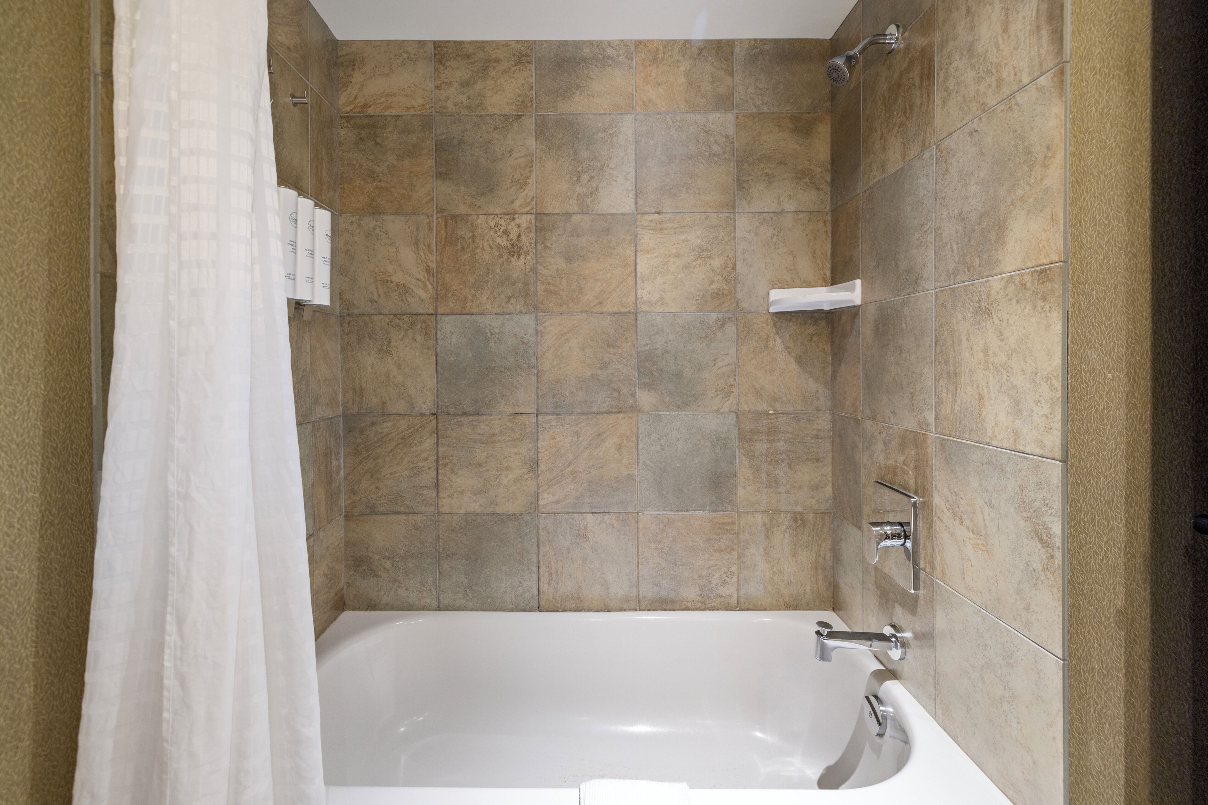 Un baño con bañera, ducha y paredes de azulejos.
