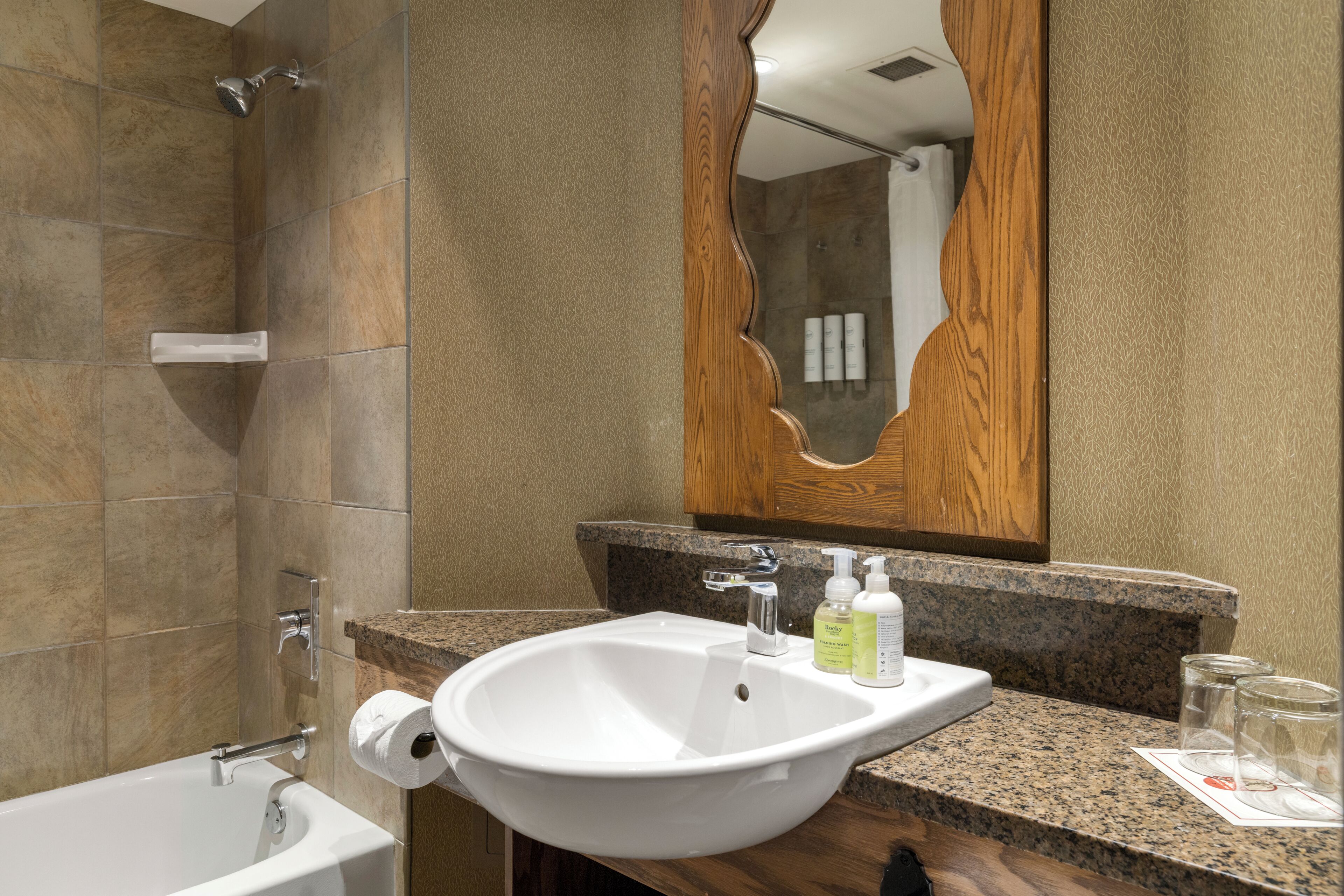 A bathroom with a bathtub, a sink, and a mirror.