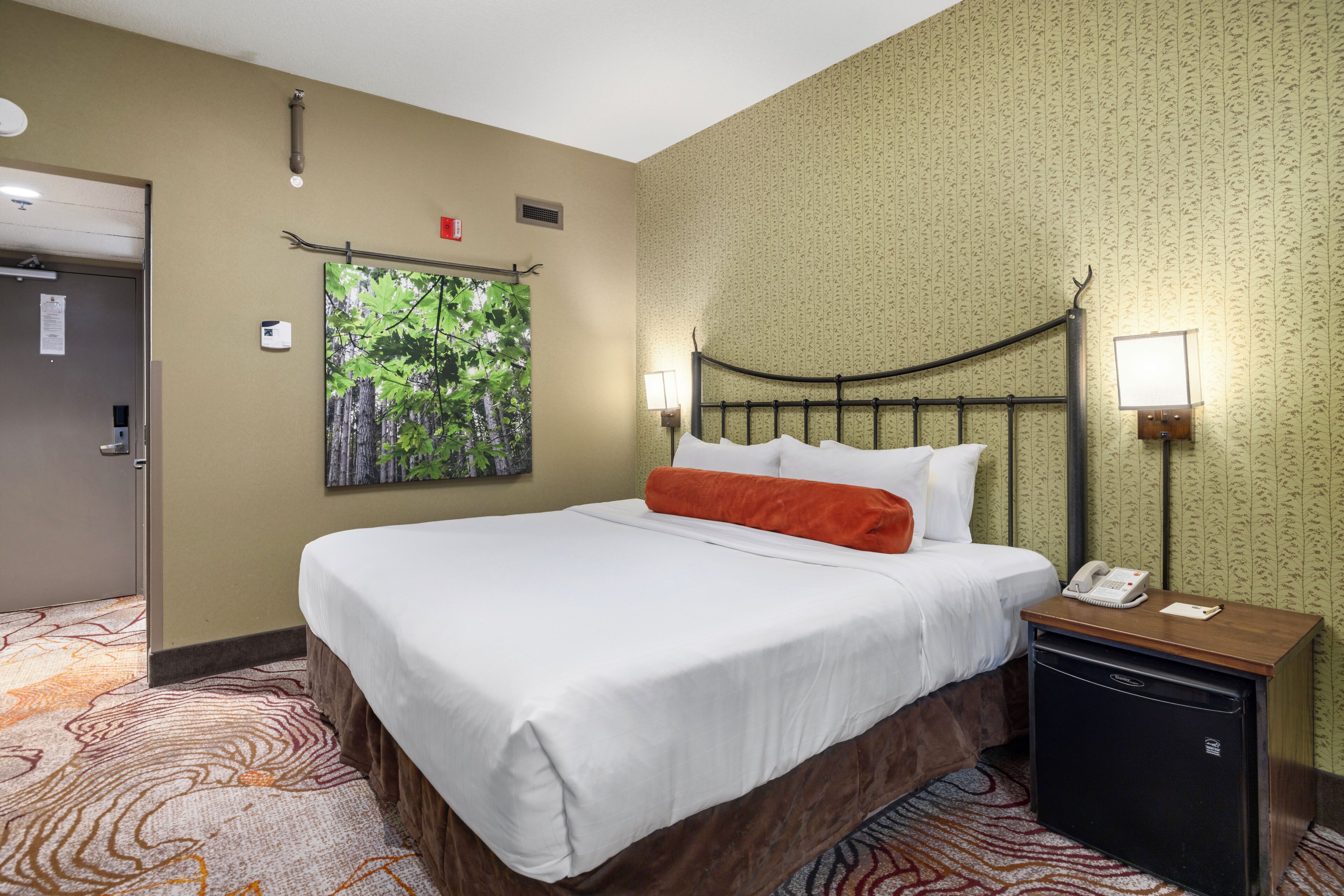 A hotel room with a bed, a nightstand, a telephone, and a painting on the wall.