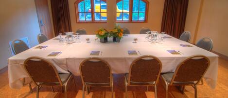 Une salle de conférence équipée d’une table ronde, de six chaises et de deux compositions florales.