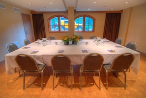 A conference room with a round table, six chairs, and two flower arrangements. - Banff Caribou Lodge and Spa (Banff)