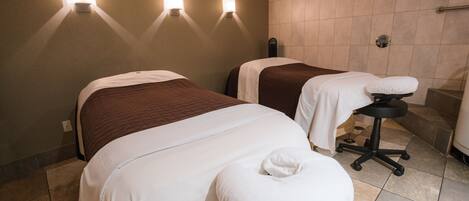 Une chambre d’hôtel avec deux lits, un fauteuil de massage et des lampes fixées au mur.