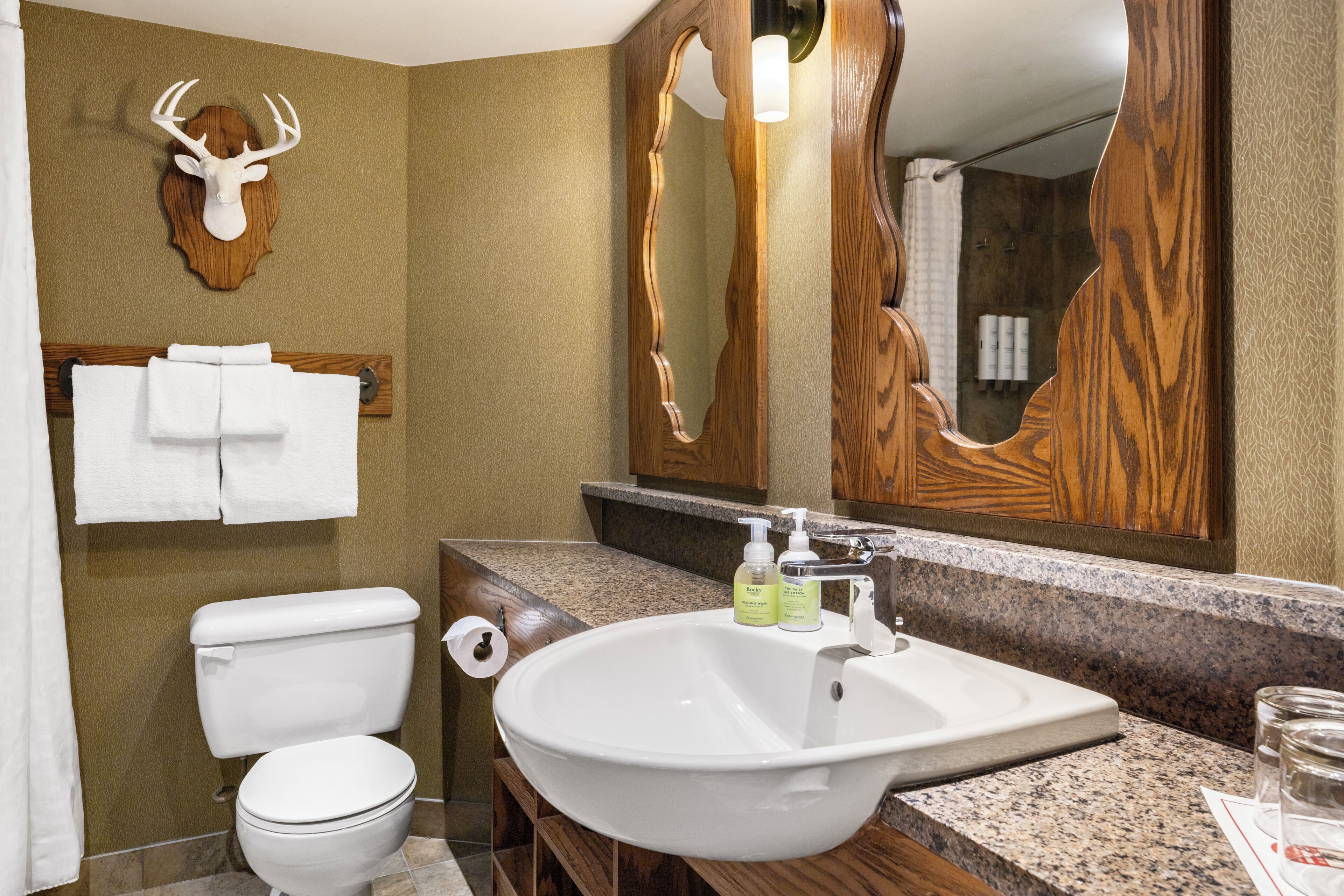A bathroom with a toilet, sink, and a mirror.