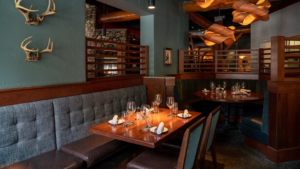 Un restaurant avec des tables et des bancs en bois, des décorations en forme de bois de cerf aux murs et un décor intérieur de style rustique.