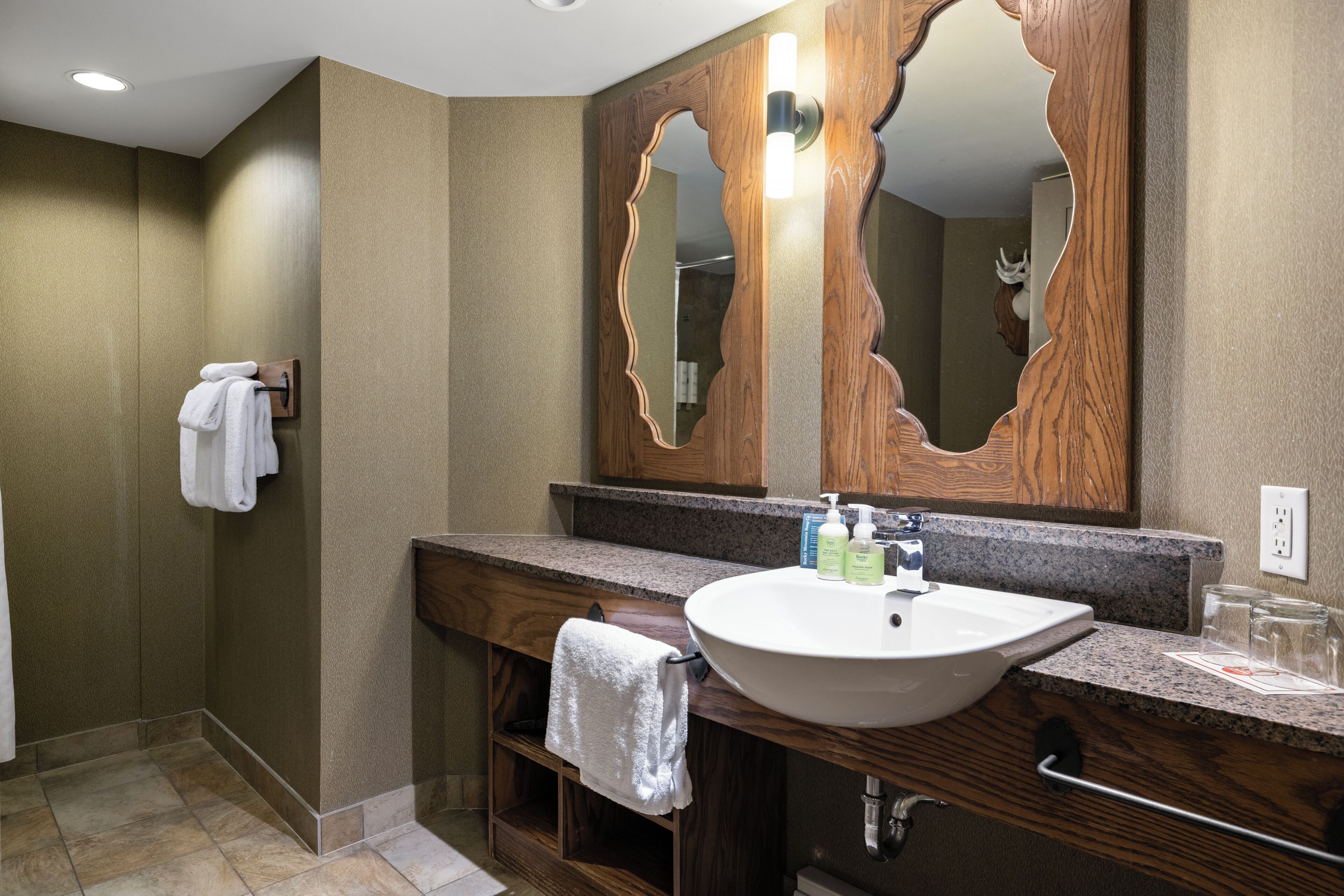 A bathroom with a large mirror, a sink, and a towel rack.