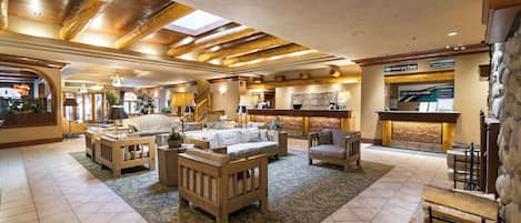 A spacious lobby with a high ceiling, wooden beams, and a mix of seating areas including sofas and chairs.