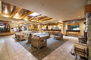 A spacious lobby with a high ceiling, wooden beams, and a mix of seating areas including sofas and chairs.