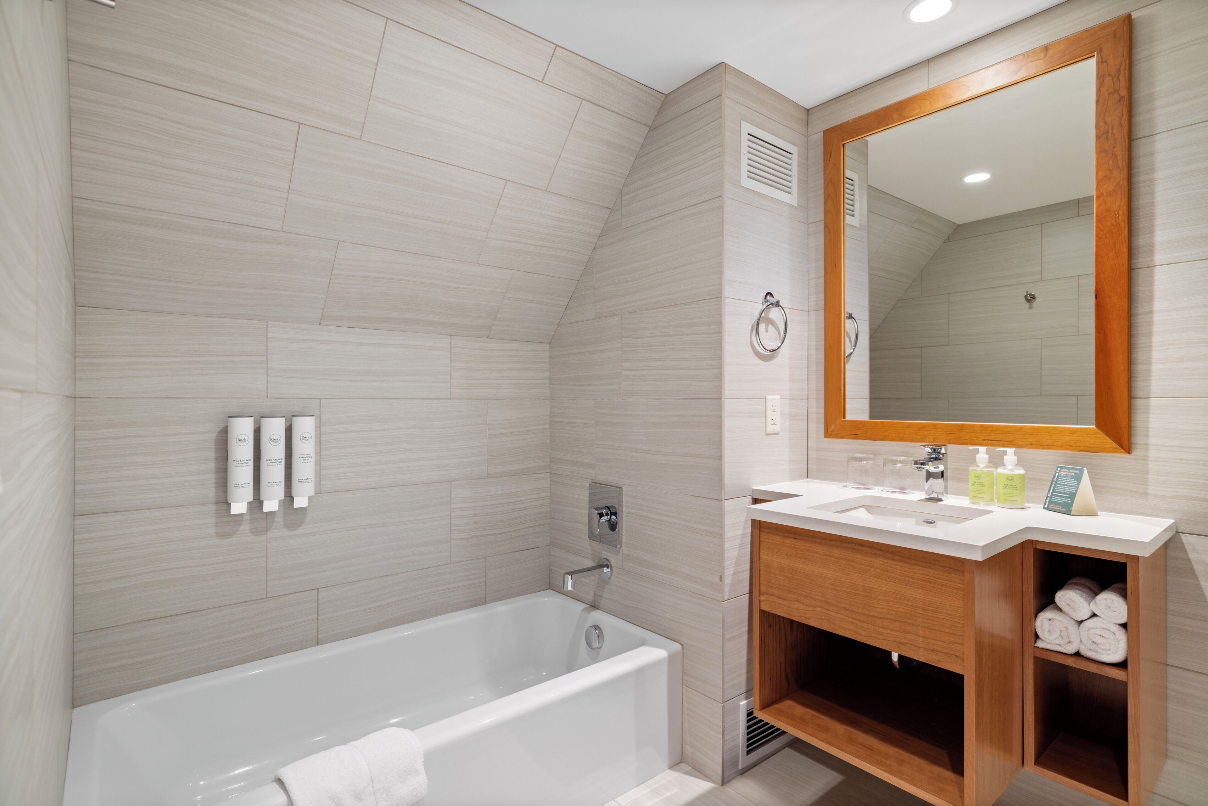 A modern bathroom with a bathtub, a vanity with a mirror, and toiletries.