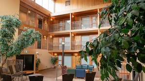 A multi-level atrium with wooden paneling, a seating area with chairs and a sofa, and potted plants.