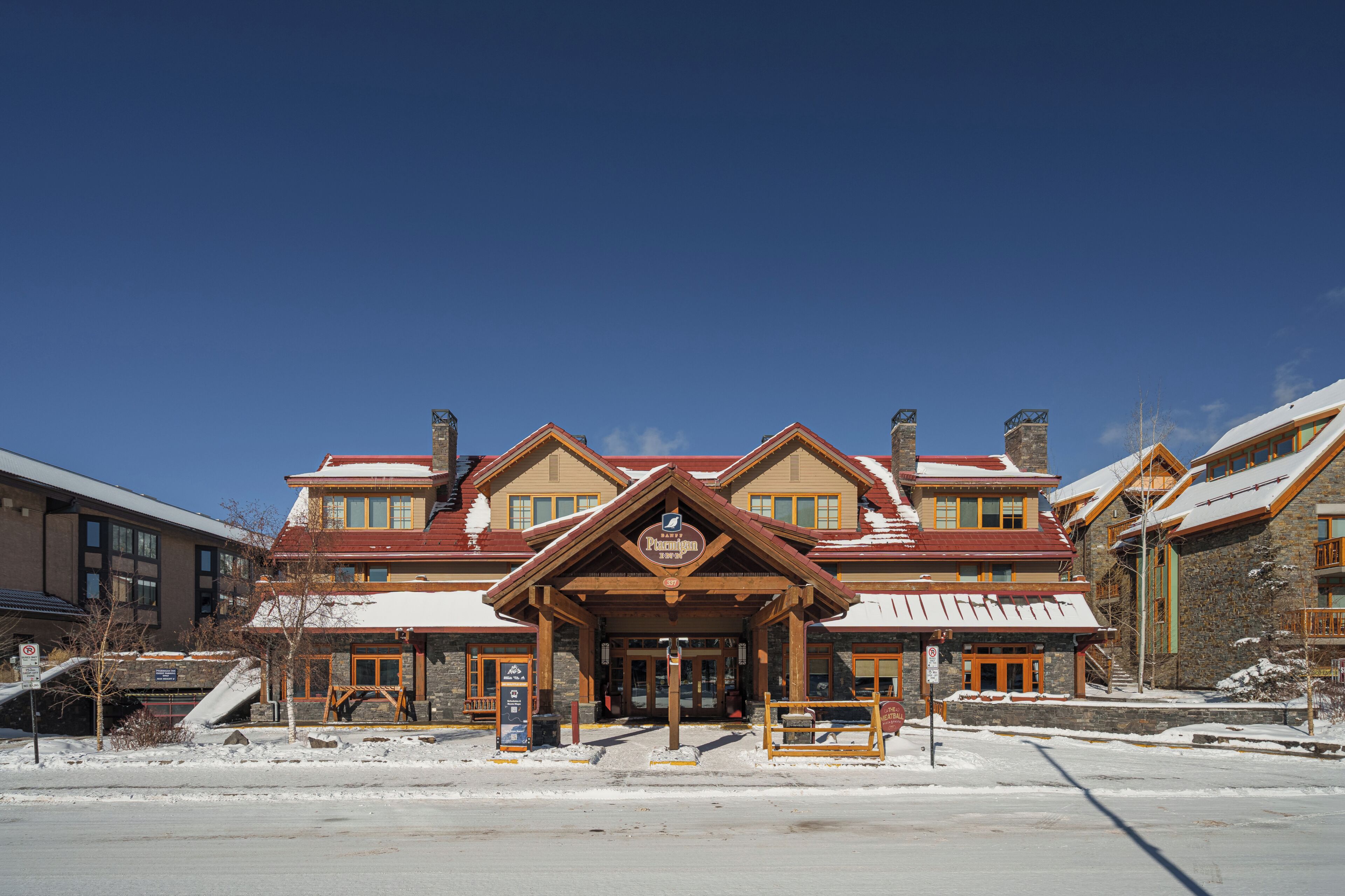 A multi-story building with a prominent entrance, stone facade, and snow-covered roof.