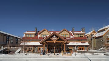 A multi-story building with a prominent entrance, stone facade, and snow-covered roof.