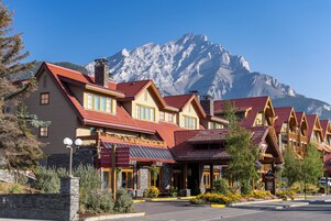 Una hilera de edificios de madera con tejados rojos, con montañas nevadas al fondo.