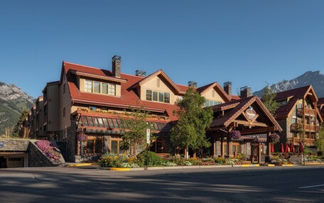 A multi-story hotel with a traditional architectural style, featuring a prominent entrance with a wooden facade and a balcony with flower boxes.