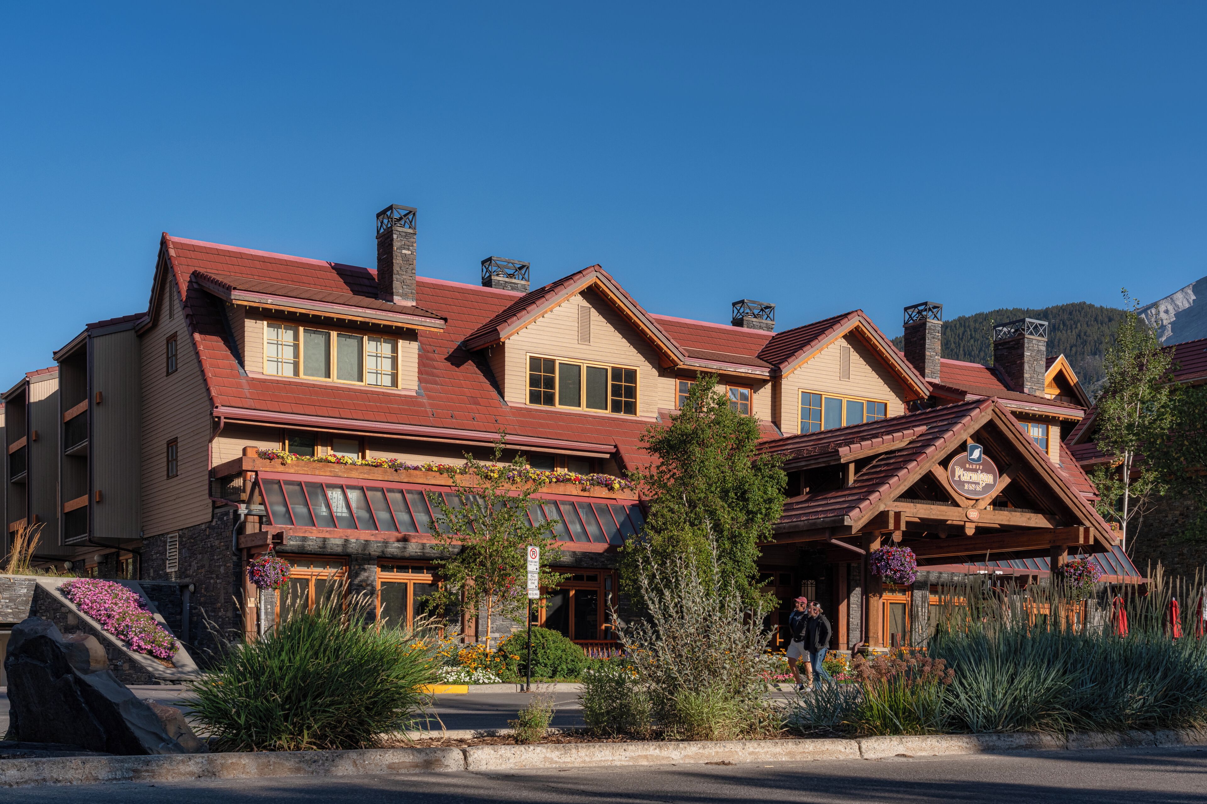A multi-story lodge with a prominent chimney, large windows, and a stone facade.