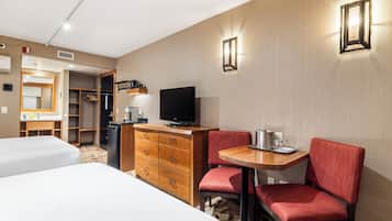 A hotel room with a bed, a desk with a chair, a television, a dresser, and a closet.