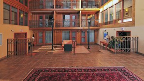 A spacious atrium with a large red patterned carpet, wooden balconies, and a central seating area.