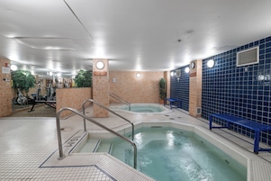 Una piscina interior con suelo de baldosas, un banco y equipo de ejercicio.