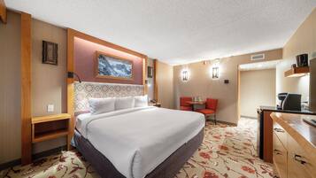 Habitación de hotel con una cama grande, un escritorio, una silla y una mesita.