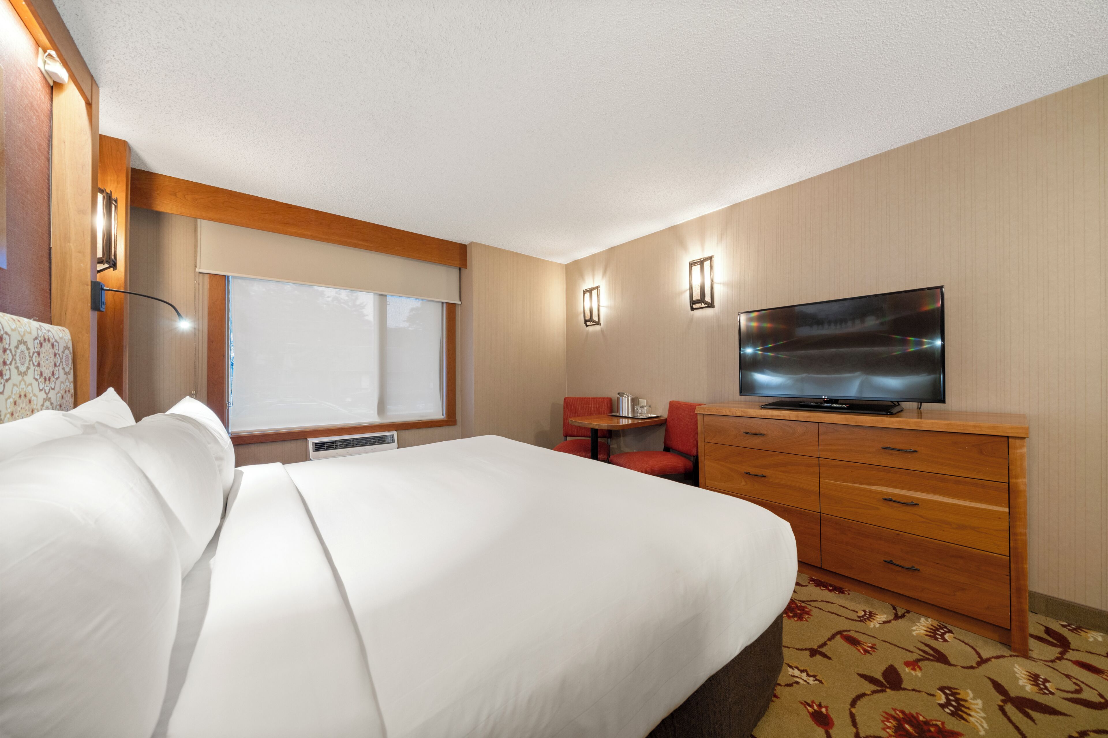 A hotel room with a bed, a television, a desk, and a chair.
