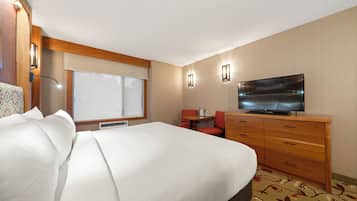 A hotel room with a bed, a television, a desk, and a chair.