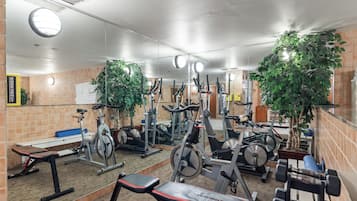 Une salle de sport équipée de divers appareils d’exercice, notamment des tapis de course, des vélos d’appartement et des poids libres.