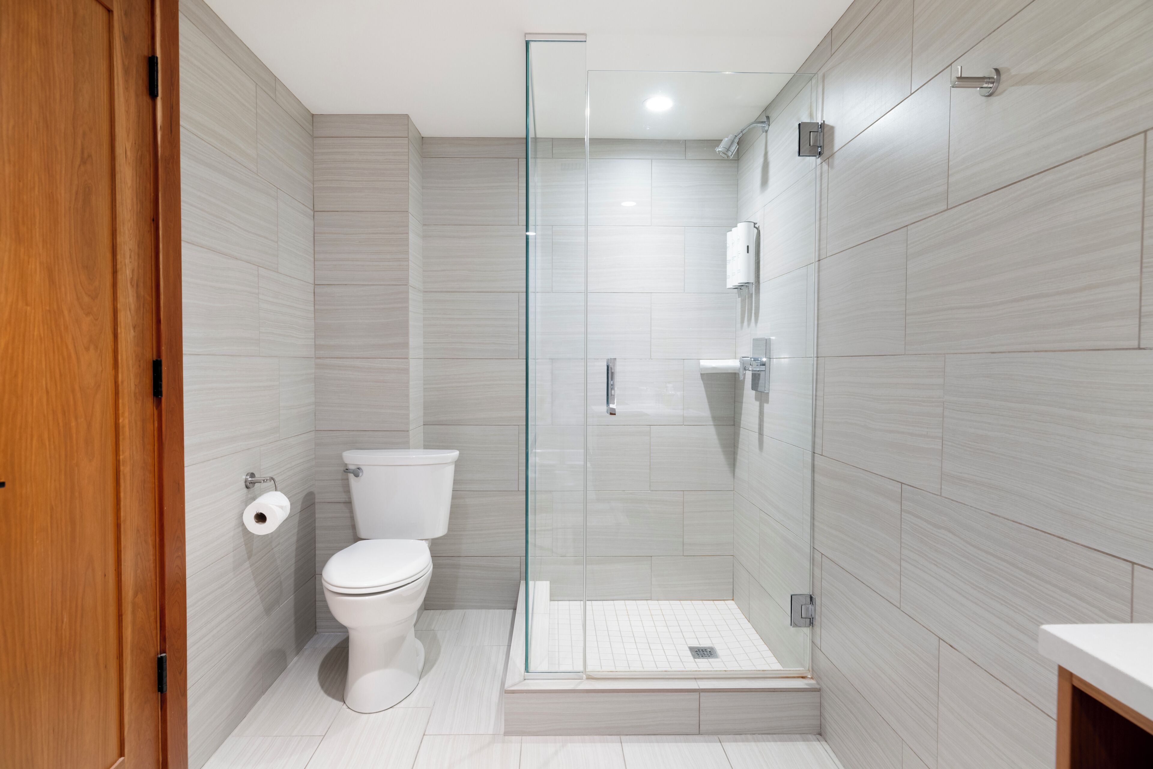 Un baño moderno con ducha de vidrio, inodoro y lavamanos.