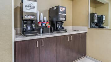 A coffee station with two coffee dispensers, a fresh coffee sign, and a coffee cup placement sign.