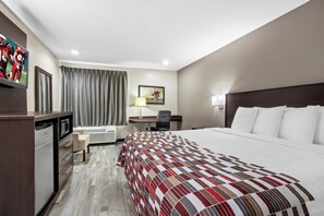 Una habitación de hotel con una cama grande, un escritorio, una silla, un televisor y un mini bar.