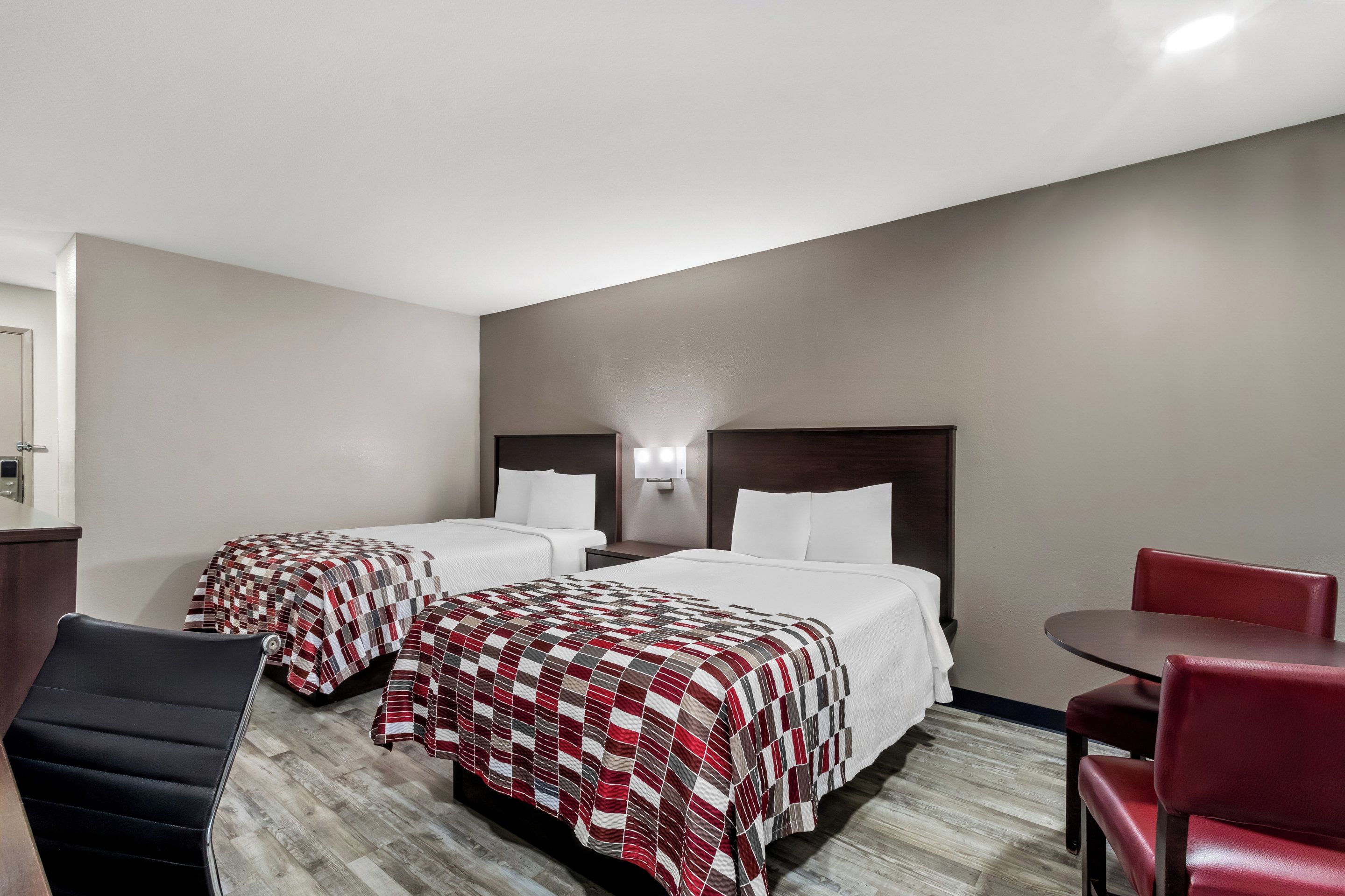 A hotel room with two beds, a desk, and a chair.