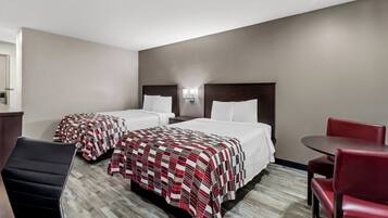 A hotel room with two beds, a desk, and a chair.