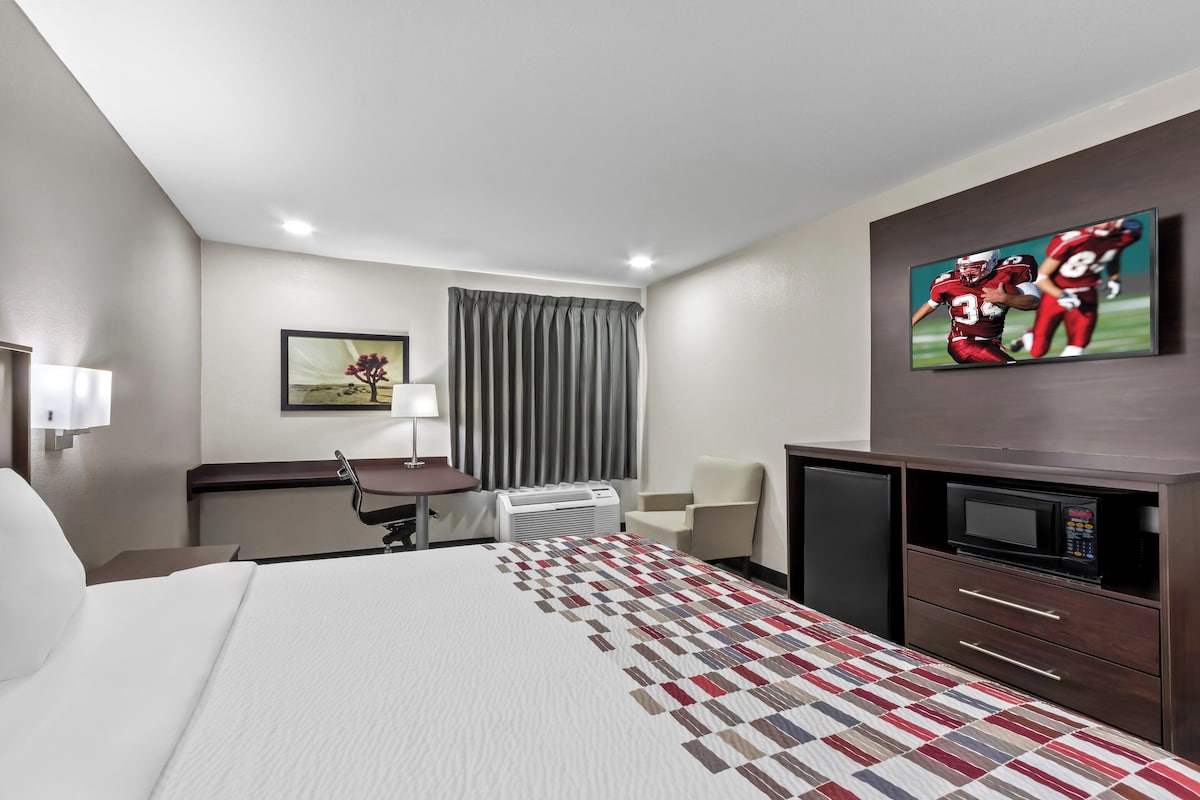 Une chambre d’hôtel équipée d’un lit, d’un bureau, d’une chaise, d’une télévision et d’un four à micro-ondes.